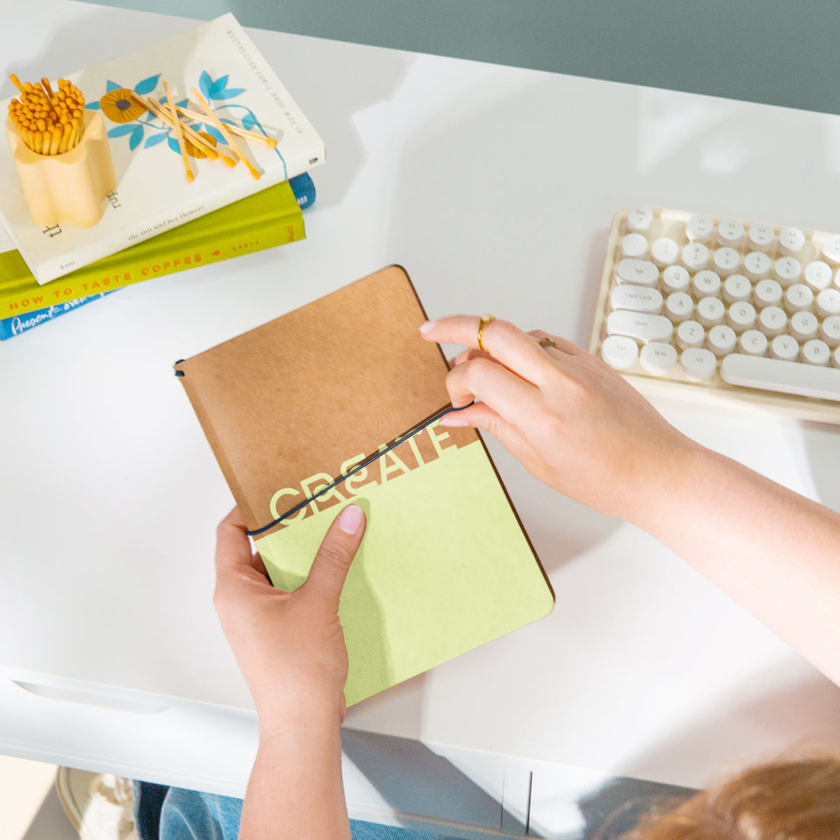 Hands holding a custom branded kraft notebook on a bright studio desk